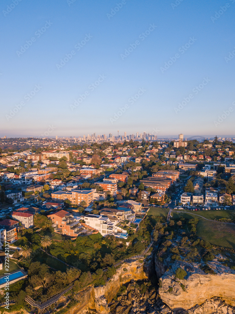 Aerial view of houses at Sydney coastline with Sydney CBD on the background.