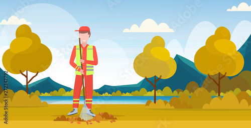 male street cleaner holding rake man sweeping lawn raking leaves cleaning service concept city park landscape background full length flat horizontal