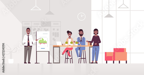 businessman presenting financial graph on flip chart to african american businesspeople team at conference meeting presentation concept modern co-working office interior full length horizontal