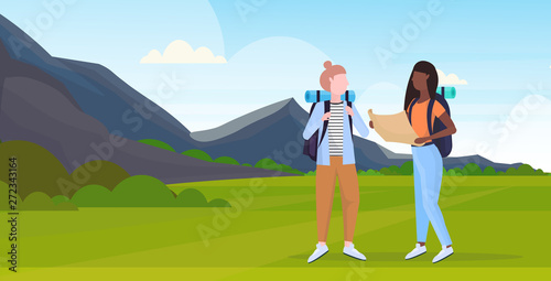 women hikers couple with backpack holding travel map mix race girls planning route hiking concept travelers on hike mountains landscape background full length horizontal flat