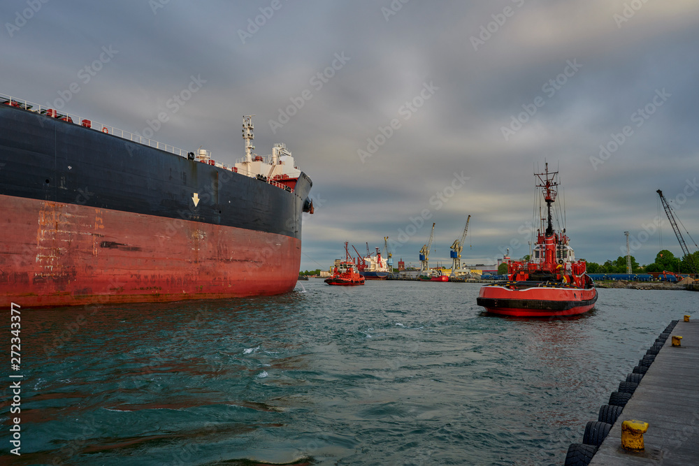 The Port of Gdansk, Gdansk, Poland - a large merchant ship in the tug boats affects the port