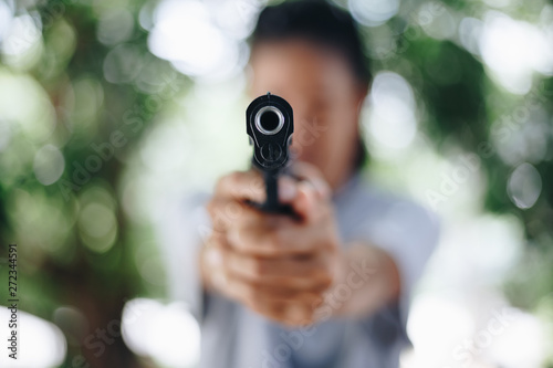 Woman pointing a gun , selective focus on front gun
