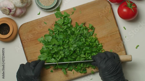 Woman's hands chopping a bunch of parsley on a wooden board