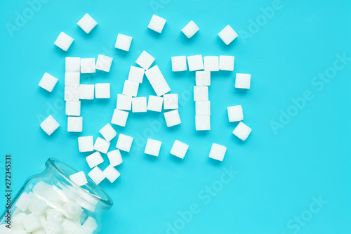 Cubes of sugar on a blue background. "Fat" text from sugar cubes.