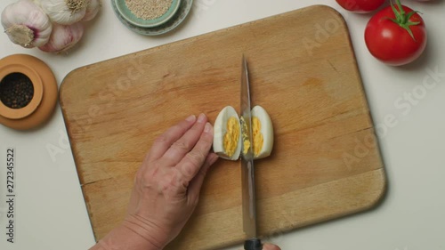 Hands cutting a hard-boiled egg on a wooden board