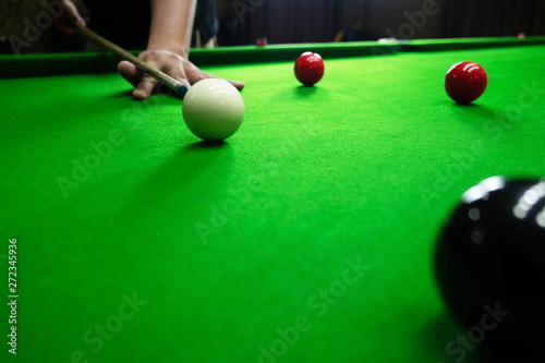 Playing snooker, piercing the red ball, black, aiming the ball and pocketing the hole to score points.