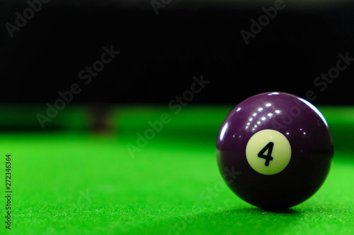 Close-up photos of billiard ball, number 4 and green floor