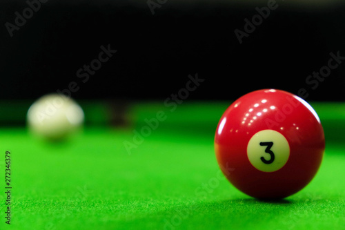 Close-up photos of billiard ball, number 3 and green floor