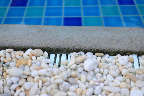 swimming pool grating covered with round white river pebble. drainage system separate lawn and pool covered with white stone. swimming pool drainage system beautiful design.