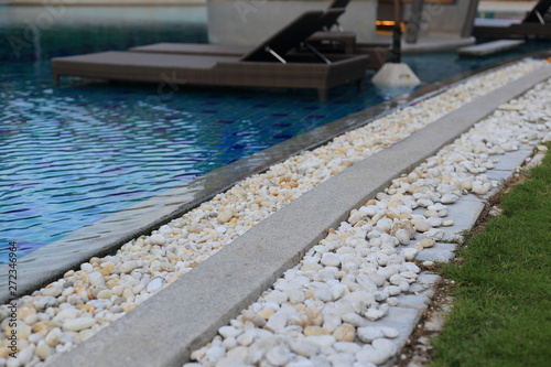 swimming pool grating covered with round white river pebble. drainage system separate lawn and pool covered with white stone. swimming pool drainage system beautiful design.