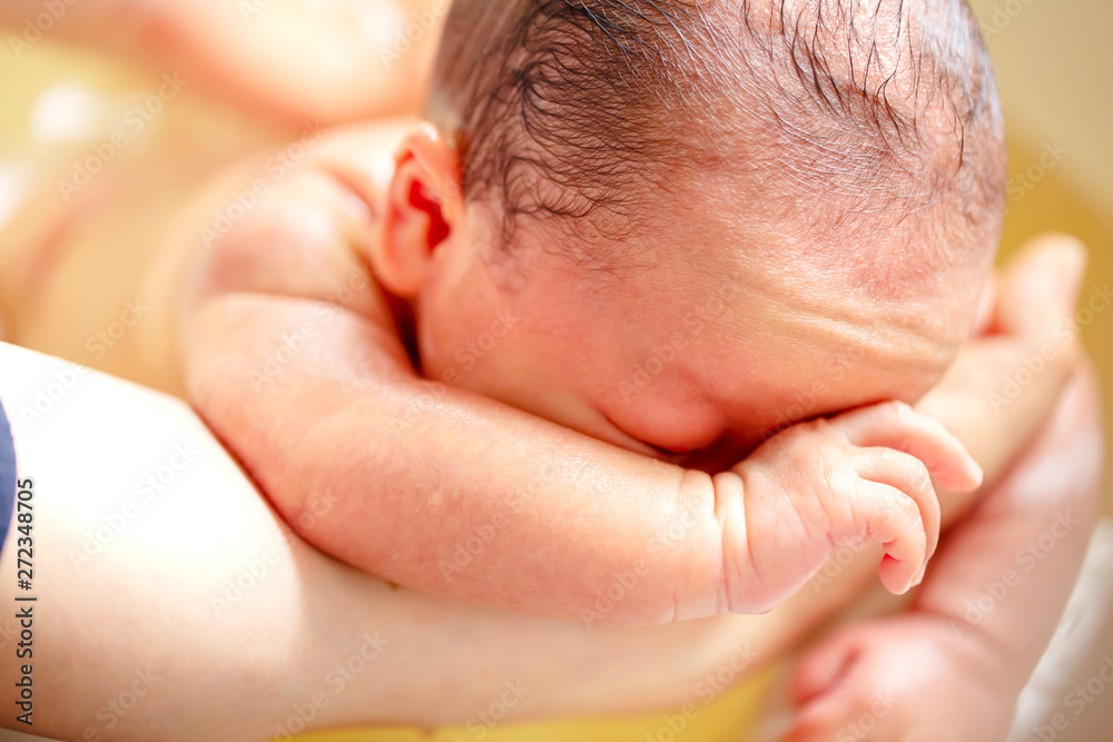 薬草の煎じ汁を入れたお風呂に浸かる生後2週間の赤ちゃんの背中を洗う Stock 写真 Adobe Stock