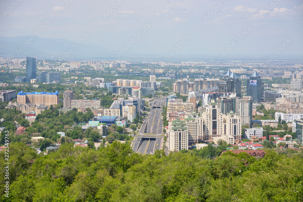 Panoramic view of the city of Almaty, with industrial zone, mountains and sky with clouds. Viewed from Kok tobe, Kazakhstan.