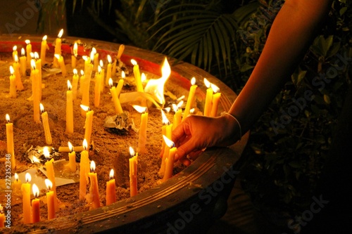 Many candles illuminate in the dark, filmed as blurred