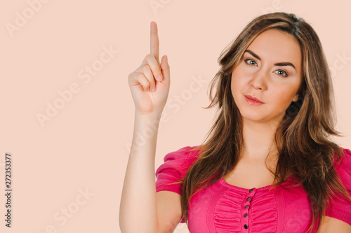 young woman pointing finger. isolated on background peach shade yellow. point towards