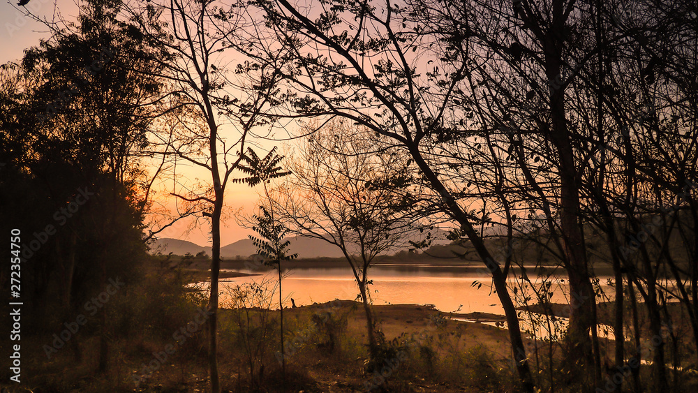 Landscape with orange and purple at sunset  silhouettes of mountains, hills and forest lake