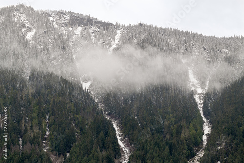 Snowy mountain peaks in the clouds above the Fraser River in British Columbia, Canada photo