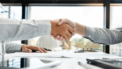 Architect and engineer construction workers shaking hands while working for teamwork and cooperation concept after finish an agreement in the office construction site, success collaboration concept