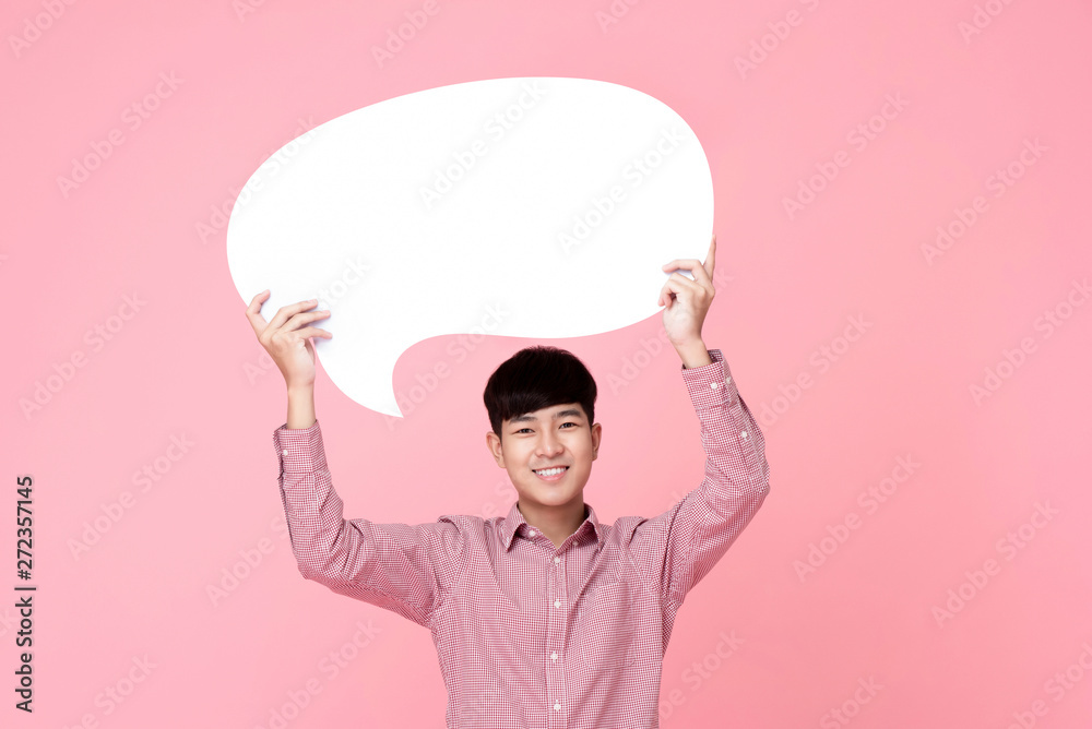 Happy smiling young handsome Asian man holding speech bubble Happy smiling young handsome Asian man holding speech bubble