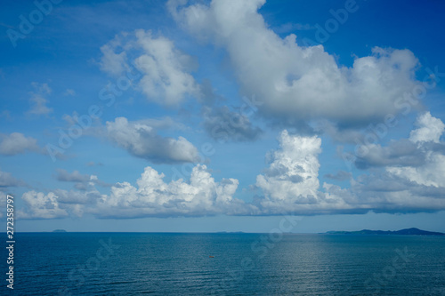 Beautiful white clouds on blue sky over calm sea with sunlight reflection