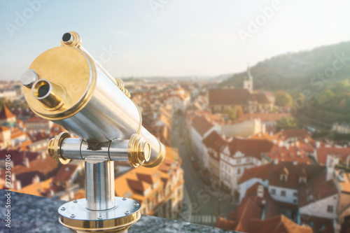 Binoculars on the viewpoint. Beautiful aerial view of the traditional old or medieval architecture in Prague in the Czech Republic is blurry ahead.