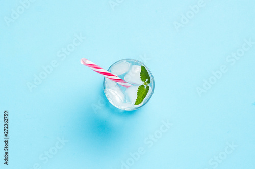 Glass of water with ice and mint on a blue background. Concept of hot summer, alcohol, cooling drink, thirst quenching, bar. Flat lay, top view