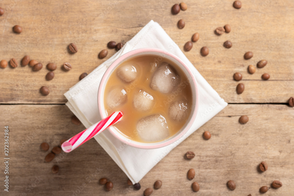 Refreshing and invigorating iced coffee in a glass and coffee grains on a wooden background. Concept coffee shop, quenching thirst, summer. Flat lay, top view Refreshing and invigorating iced coffee in a glass and coffee grains on a wooden background. Concept coffee shop, quenching thirst, summer. Flat lay, top view