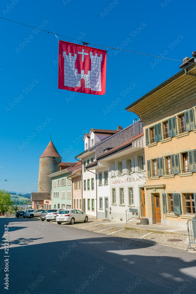 historic city center of the medieval Swiss village of Romont in canton Fribourg with city flag in foreground