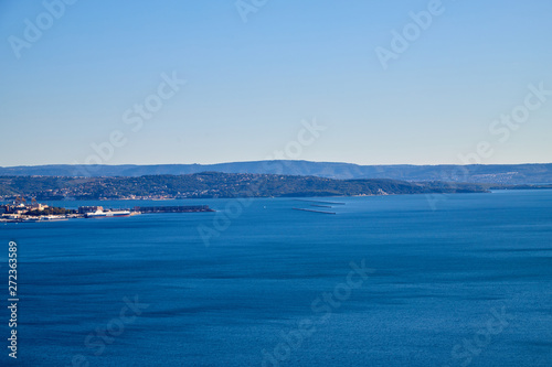 View from a high cliff with greenery to the sea, blue sky, white clouds and ships on a Sunny day