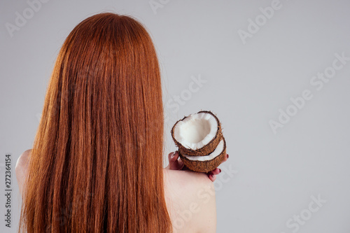 young ginger redhead woman with ideal skin and perfect redhaired hear holding coco nut in hands in white studio backgroung.