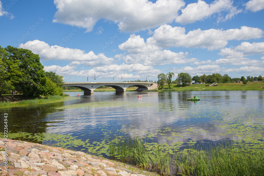 City Jelgava, Latvian Republic. River Lielupe, people are driving catamaran. Bridge and water. Jun 9. 2019. Travel photo. City Jelgava, Latvian Republic. River Lielupe, people are driving catamaran. Bridge and water. Jun 9. 2019. Travel photo.
