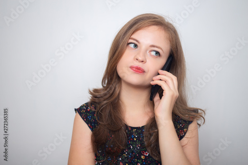 Young caucasian woman with mobile phone looks annoyed, irritated or moody