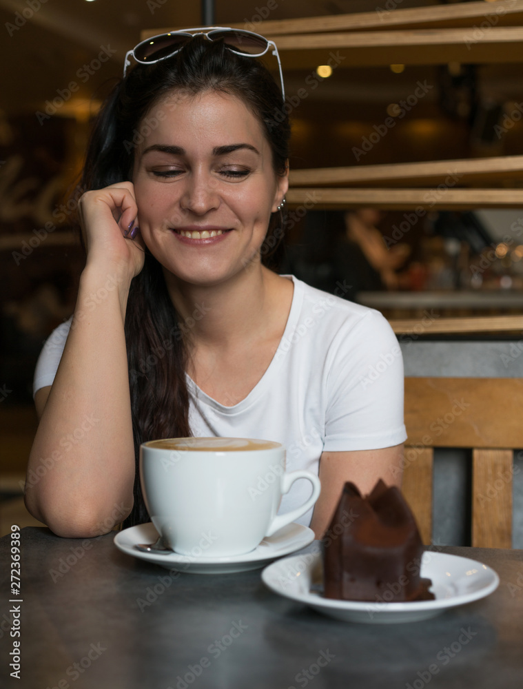 Woman eats chocolate cake and drinks coffee in cafe. Lifestile photo with a girl in white Woman eats chocolate cake and drinks coffee in cafe. Lifestile photo with a girl in white