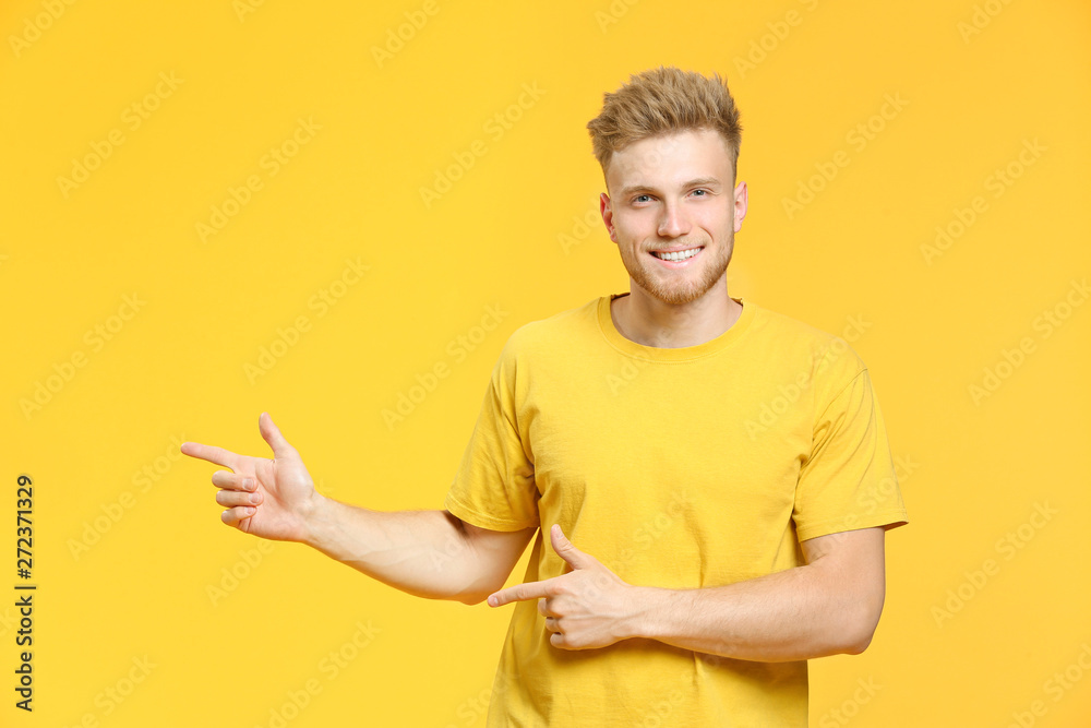 Portrait of handsome young man pointing at something on color background Portrait of handsome young man pointing at something on color background