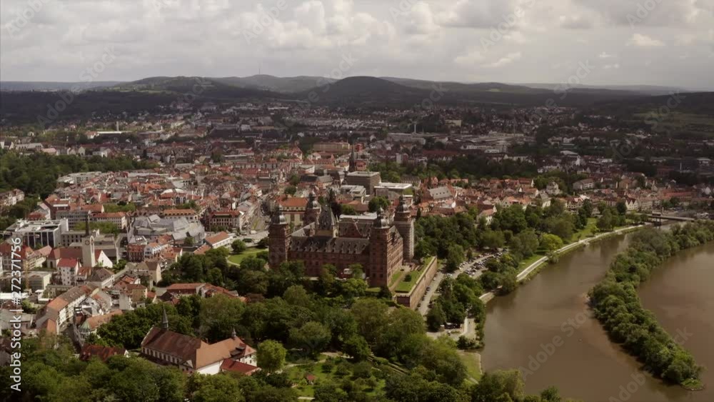 The river Main with the cityscape of Aschaffenburg, Germany, in a smooth aerial shot. The drone is showing the whole city from above. The river Main with the cityscape of Aschaffenburg, Germany, in a smooth aerial shot. The drone is showing the whole city from above.