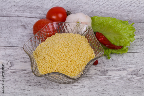 Raw couscous in the bowl served salad leaves, tomato and pepper photo