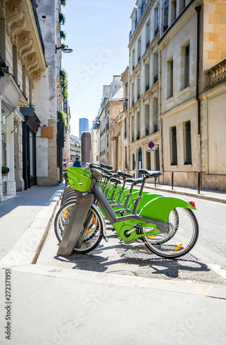 Green ecological electric bicycles with baskets for public rent await tourists cyclists on the streets of Paris
