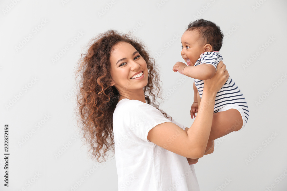Happy African-American mother with cute little baby on light background Happy African-American mother with cute little baby on light background