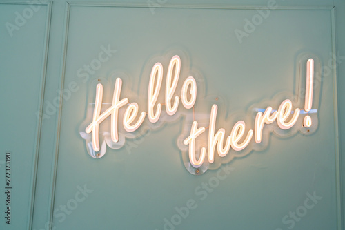 Neon glowing sign with word Hello there and green wall