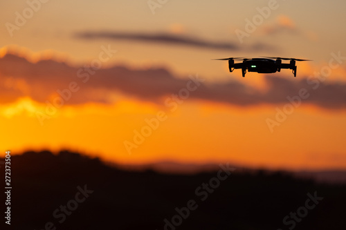Flying silhouette of drone against sunset. Flying silhouette of drone against beautiful sunset sky