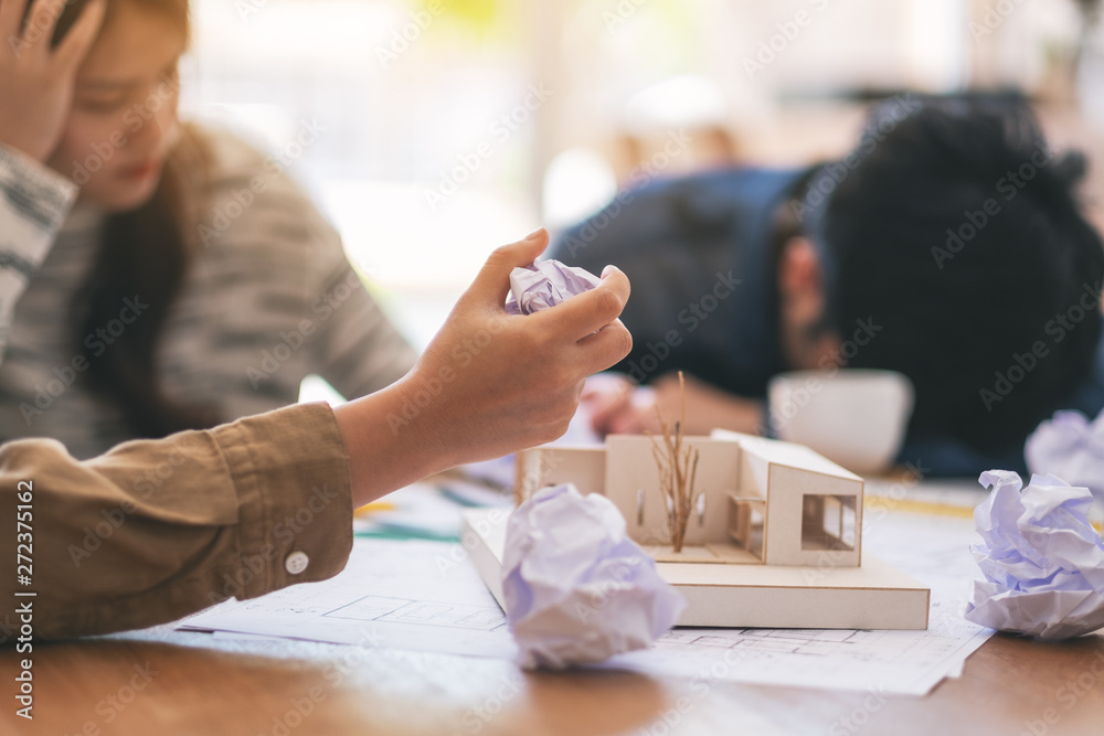 Obraz premium An architect screwed up papers by hand when feel stressed after working on architecture model together with shop drawing paper in office