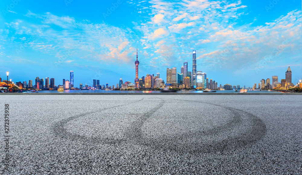 Fototapeta premium Asphalt race track ground and modern skyline and buildings in Shanghai at night,panoramic view