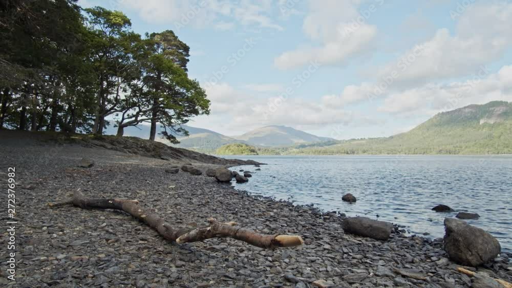 Panning shot of English lake in Cumbria, Beach in foreground Panning shot of English lake in Cumbria, Beach in foreground