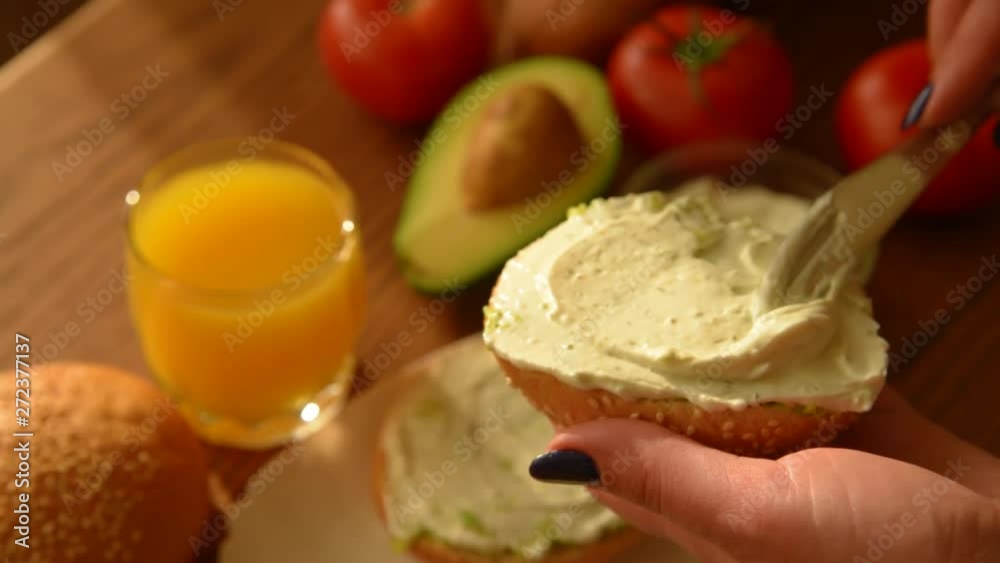 Woman spreading creamy cheese on avocado toast Woman spreading creamy cheese on avocado toast