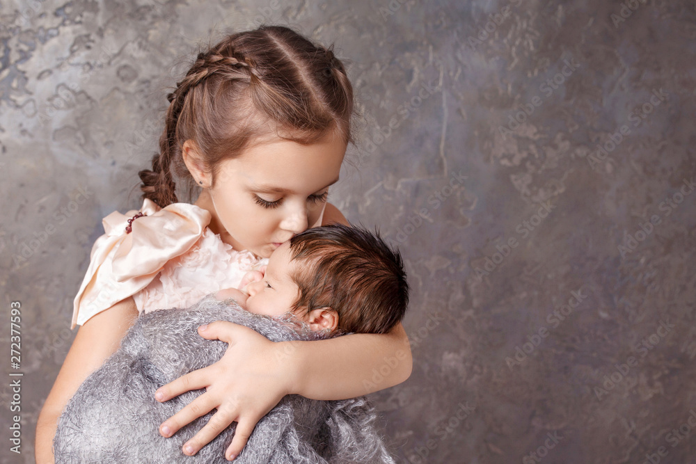 Foto de Newborn baby with sister. Cute girl kissing her little brother