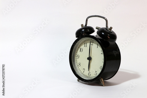Twin bell alarm clock black color on six o'clock put on the white floor.
