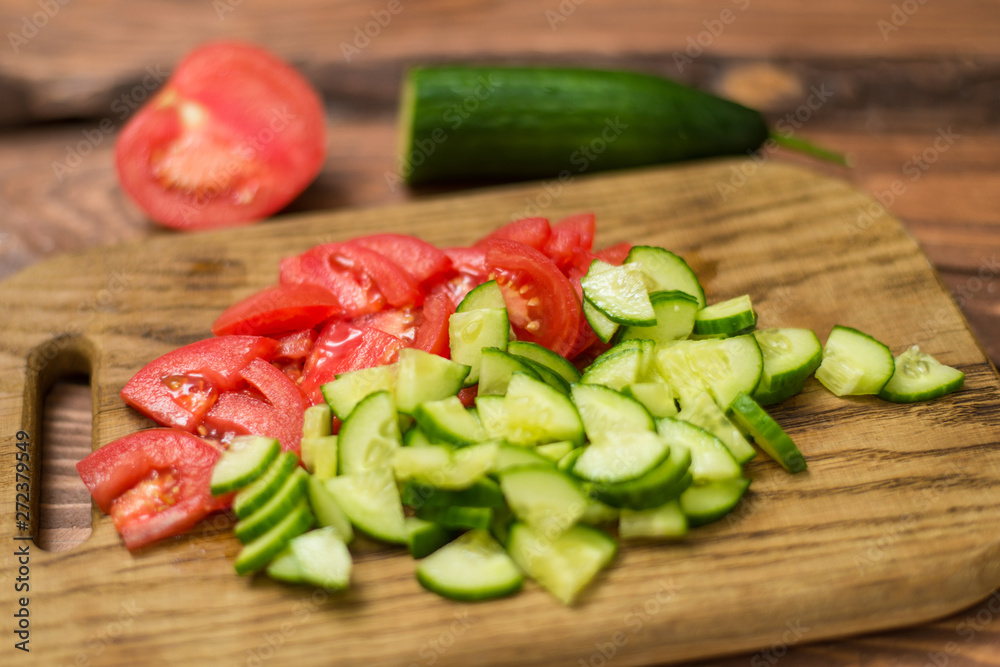 Sliced fresh tomato and cucumber on a wooden board. Cooking vegetable salad. The concept of healthy, vegan food. Sliced fresh tomato and cucumber on a wooden board. Cooking vegetable salad. The concept of healthy, vegan food.