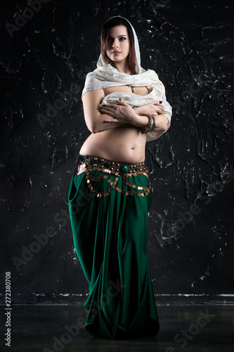Sexy women performs belly dance in ethnic dress on black background, abstract art photography