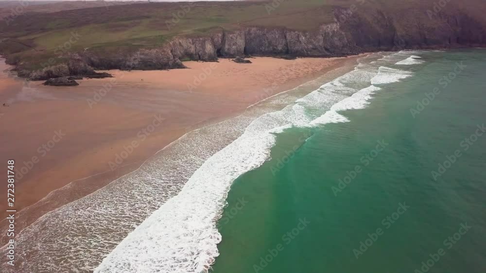Flyover wide drone-shot of waves lapping onto an empty sandy beach. Newquay, Cornwall. Flyover wide drone-shot of waves lapping onto an empty sandy beach. Newquay, Cornwall.