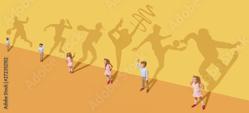 Childhood and dream concept. Conceptual image with children and shadow on the yellow studio wall. Little girl and boy want to become gymnast  dancer  artist  boxer  runner or football player.