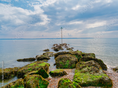 Rocks covered in seaweed on the beach at Lee on Solent reach out in to the river. photo